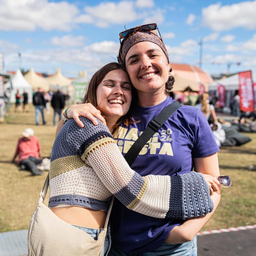 Twee jonge vrijwilligers omhelzen elkaar bij ManiFiesta