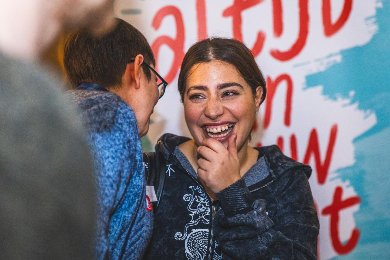 Manal Toumi lachend in gesprek met een andere persoon.