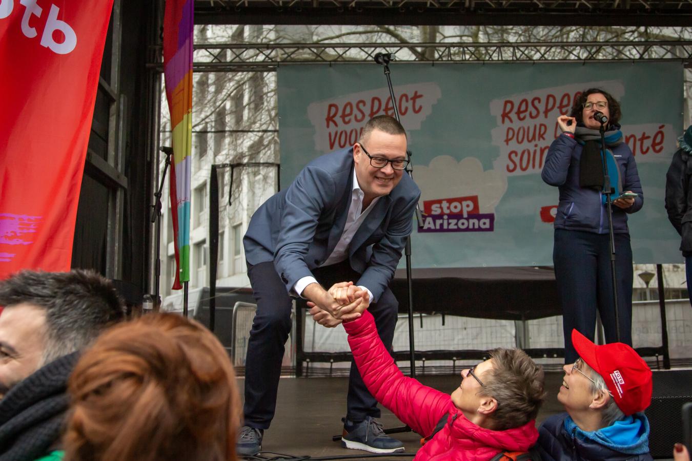 Raoul Hedebouw schudt de hand van betogers op de betoging van de non-profit.