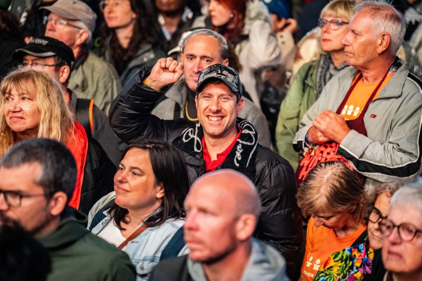 Een man in het publiek steekt een vuist in de lucht en lacht