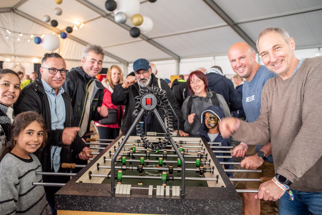 Een gemengde groep mensen speelt tafelvoetbal