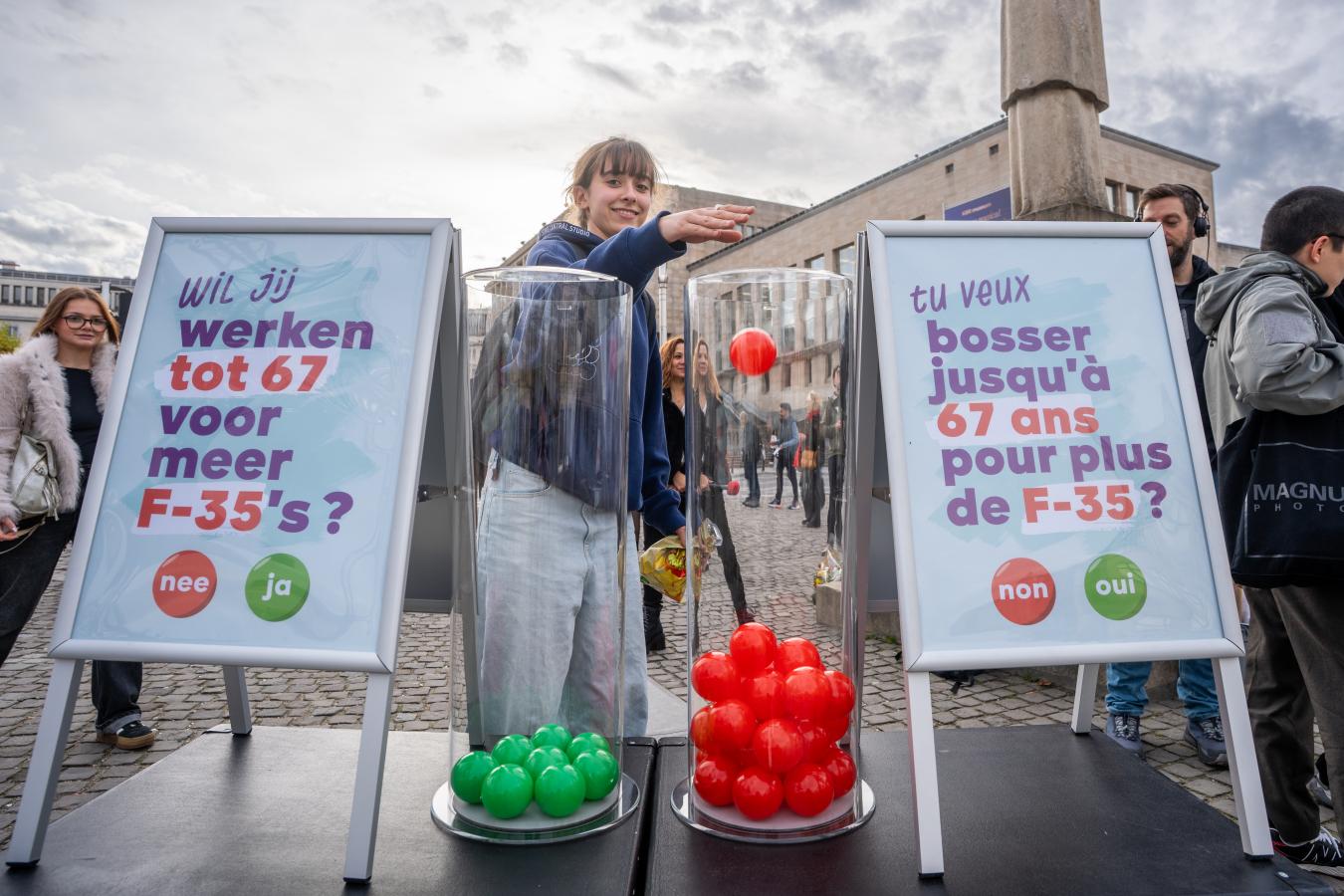 Een jonge vrouw stopt een rode bal in de bak met ‘nee’ om te stemmen over de vraag ‘Wil je tot je 67e werken voor meer F-35's?’.