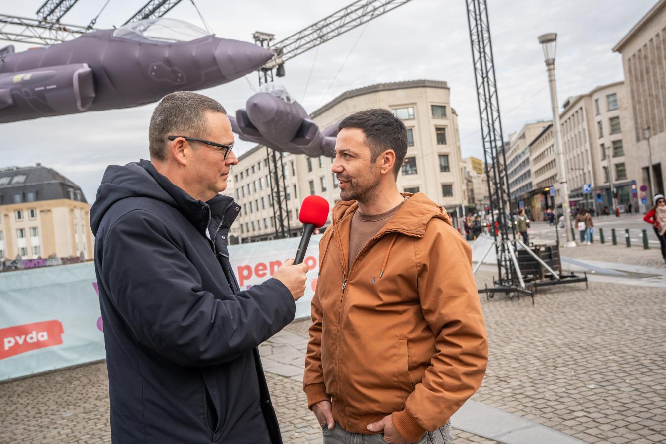 Raoul Hedebouw streckt das Mikrofon aus, um einen Mann zu interviewen.