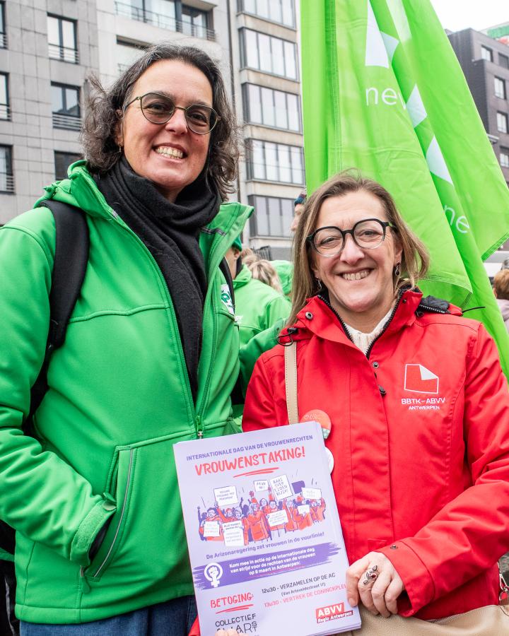 Twee vrouwen in vakbondskleding delen flyers uit voor de vrouwenstaking op 8 maart.