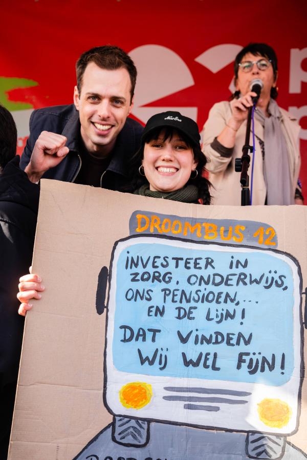 beeld 5: Jos D’Haese poseert voor een selfie met een vrouw die een bord in de handen heeft tegen de besparingen bij De Lijn