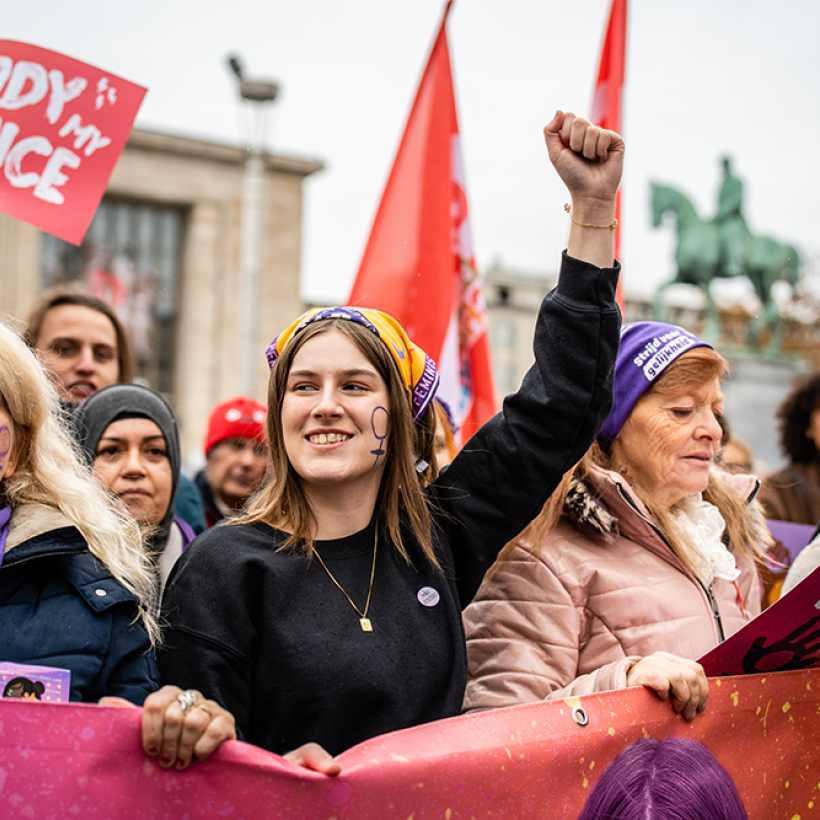 Een jonge vrouw van PVDA-vrouwenbeweging Zelle met de vuist in de lucht tijdens een betoging voor vrouwenrechten