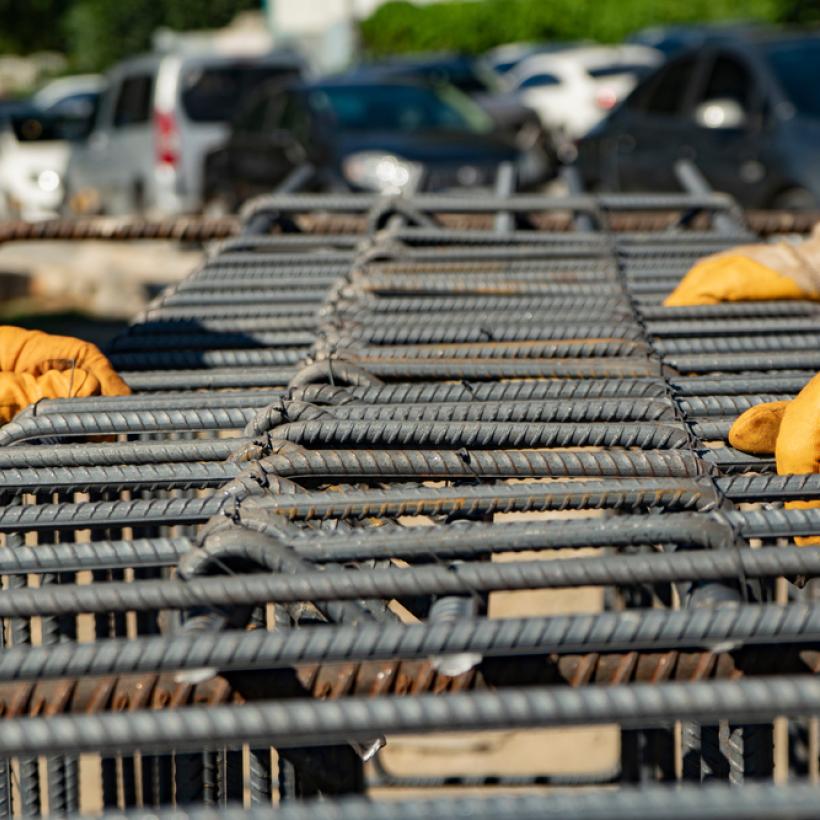 Arbeider op de bouwplaats die een metalen raamwerk maakt voor het storten van beton. 