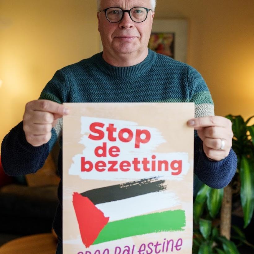 Peter Mertens houdt een poster vast die oproept tot het beëindigen van de bezetting van Palestina.