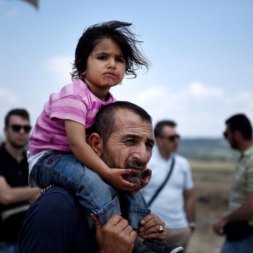 Een vader met zijn dochter op zijn schouders 