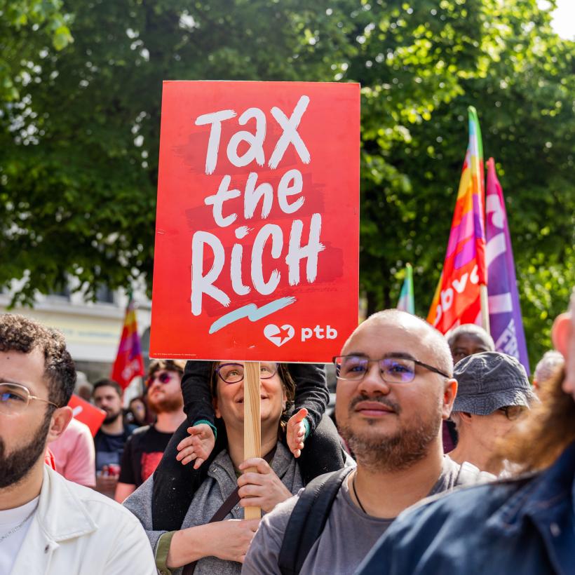 Een bord “Tax The Rich” midden in een demonstratie.