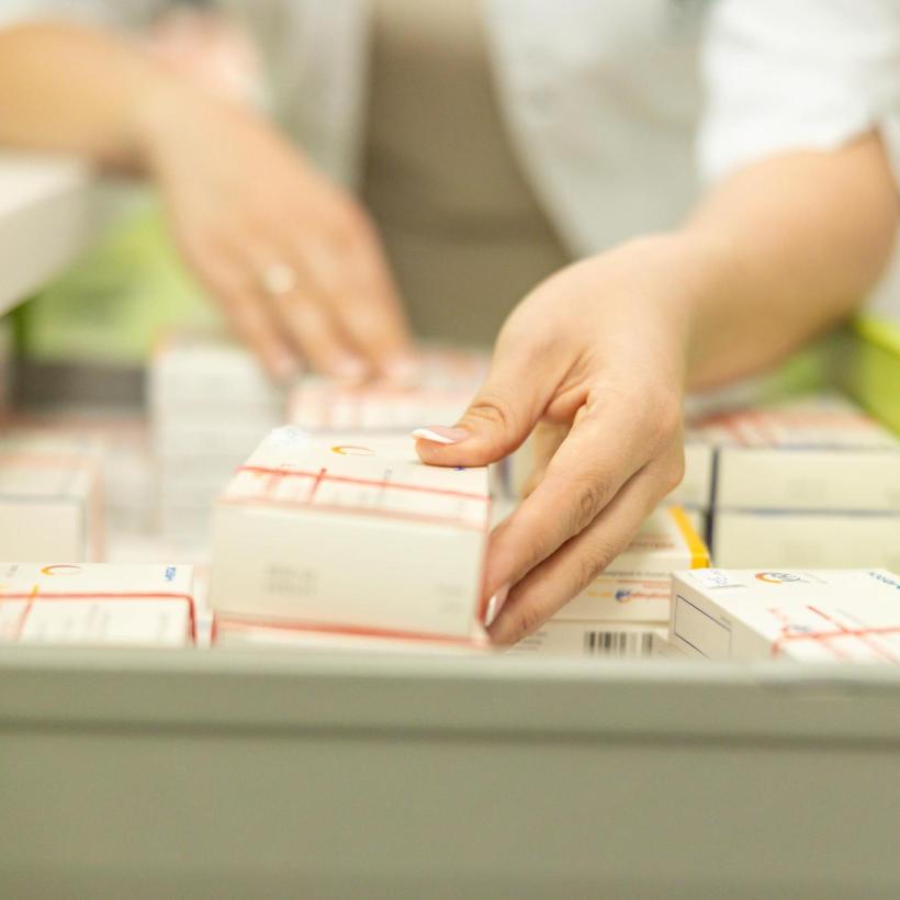 Een apotheker legt medicijnen in een lade