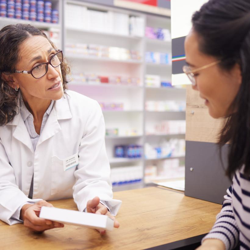 Een apotheker verkoopt een doos geneesmiddelen aan een klant.