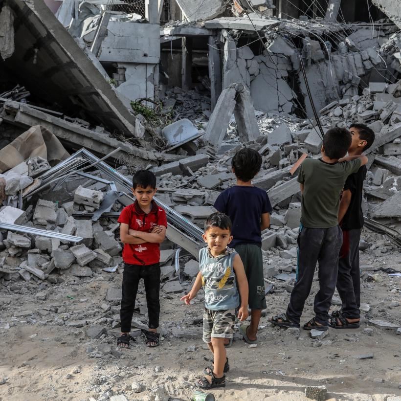 Palestijnse kinderen kijken naar een verwoest gebouw na een Israëlische luchtaanval.