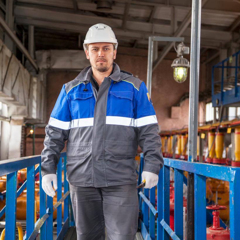 Een arbeider in een fabriek kijkt in de lens van de camera