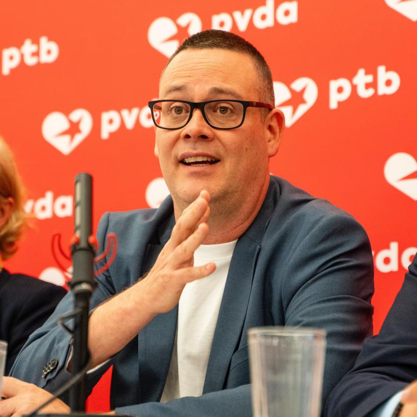 Raoul Hedebouw voor een microfoon tijdens een persconferentie