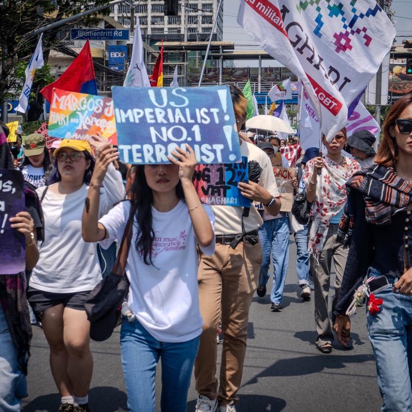 Betoging op 27 maart in 2026 in Manilla. Een jonge vrouw draagt een bord mee: “US imperialist, number 1 terrorist”