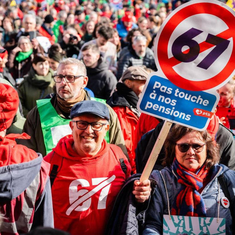 Een man middenin een grote vakbondsbetoging. Hij houdt een bord vast tegen de pensioenleeftijd op 67 jaar 