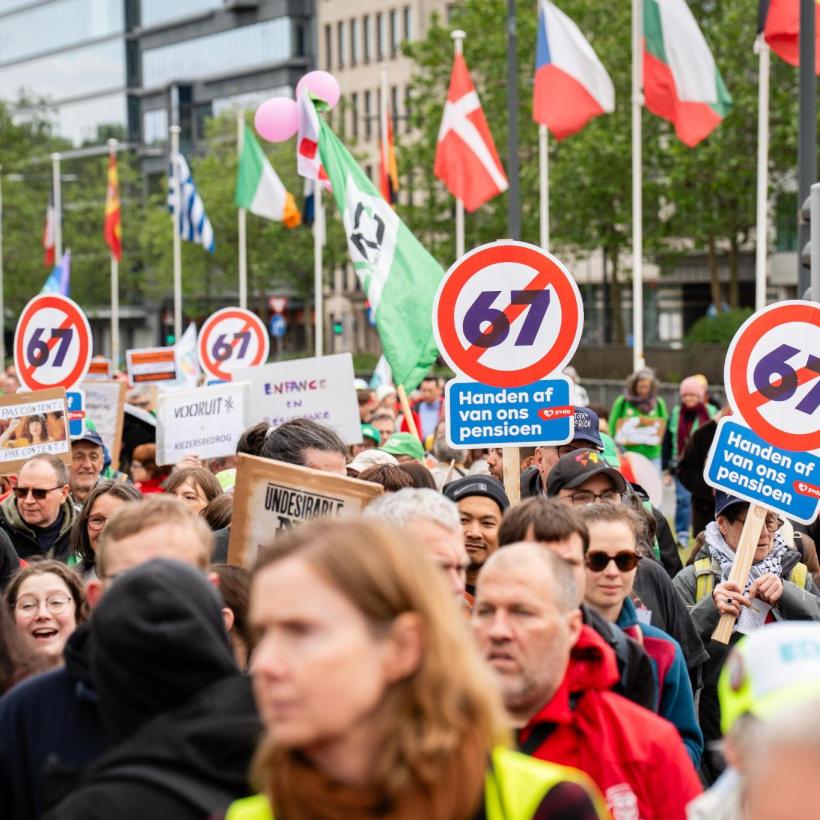 Beeld van een massa betogers tijdens een betoging tegen de regering-De Wever-Rousseau. Op enkele bordjes is te lezen ‘Handen af van ons pensioen’
