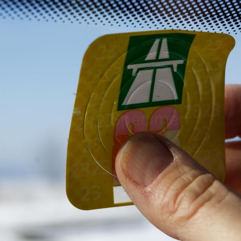 Een wegenvignet wordt tegen de voorruit van een auto gekleefd