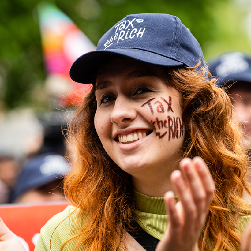 Une femme porte une casquette avec l'inscription "Tax the rich" lors d'un rassemblement du 1er Mai du PTB.
