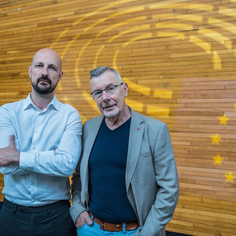 Marc Botenga en Rudi Kennes poseren in de wandelgangen van het Europees parlement.