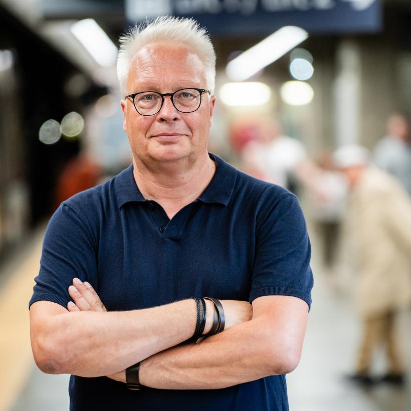 Peter Mertens staat met zijn armen gekruist in een metrostation