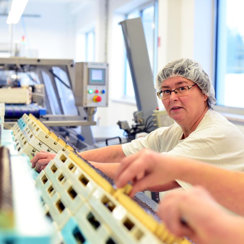 Une travailleuse à la chaîne dans une usine de production alimentaire.
