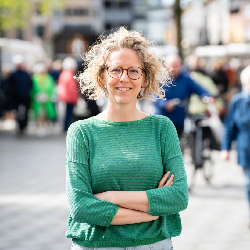 Greet Daems met gekruiste armen in een straatbeeld