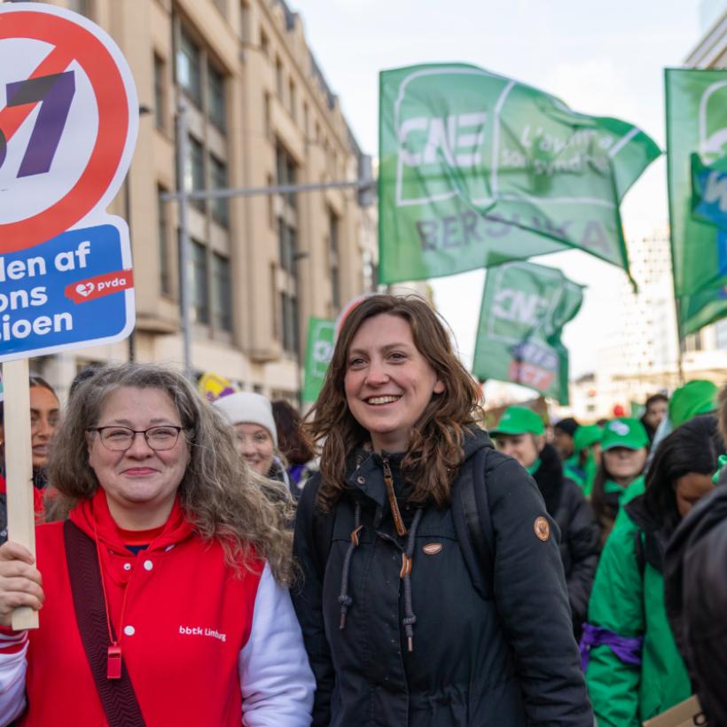 Line De Witte tijdens de nationale betoging van 12 maart, naast een dame met een bord ‘handen af van ons pensioen’
