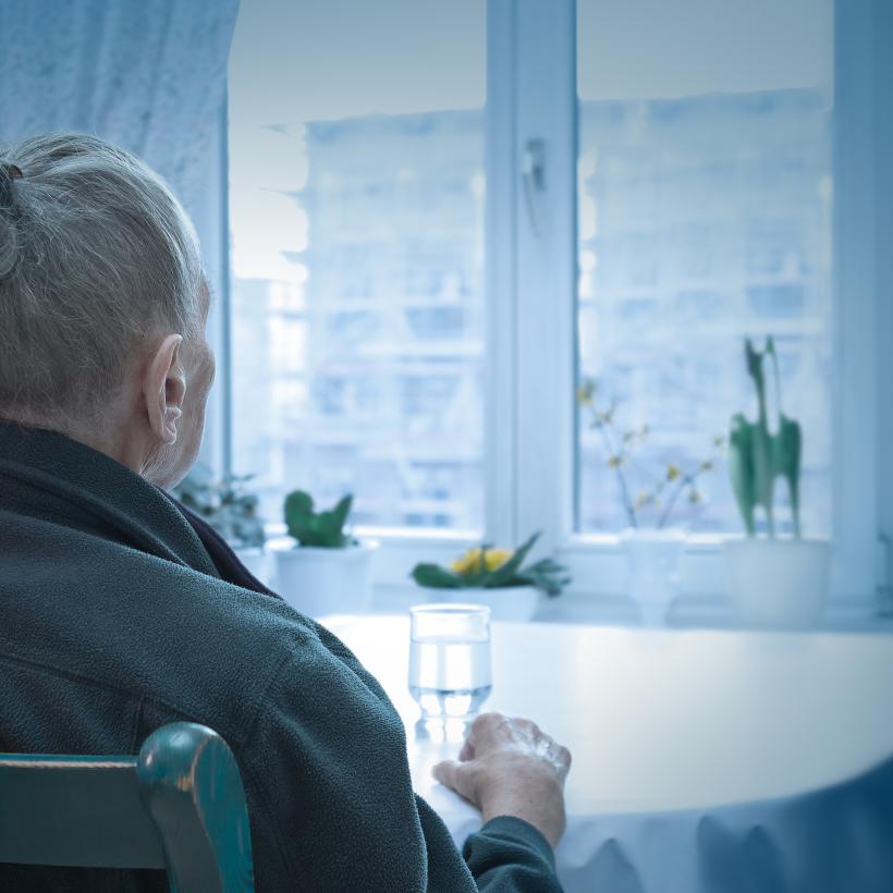 Oudere vrouw kijkt door het raam