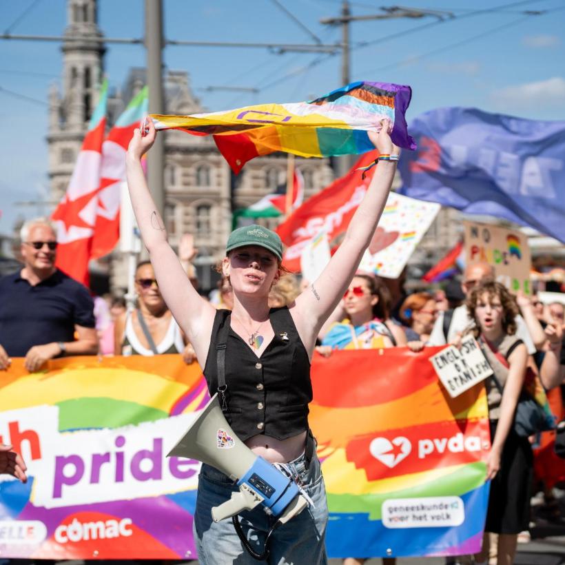 PVDA-blok op een Pride-parade, met vooraan een persoon die de regenboogvlag laat wapperen