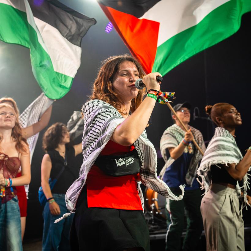 Des jeunes chantent et portent des drapeaux palestiniens sur scène à ManiFiesta