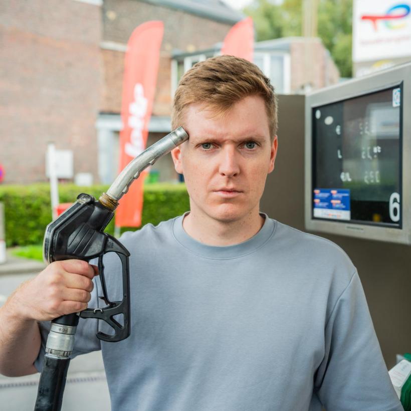 Man aan een tankstation houdt het pomppistool tegen zijn hoofd en kijkt boos