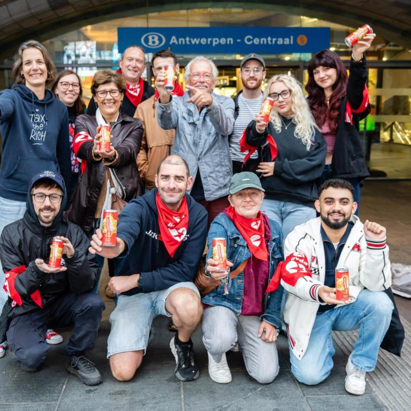 PVDA-militanten voor het station van Antwerpen-Berchem tonen het blikje dat ze uitdeelden aan de pendelaars