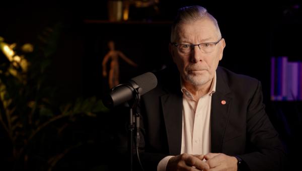 Rudi Kennes in een studio achter een microfoon.