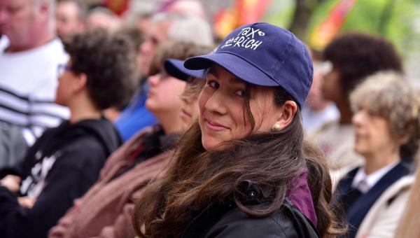 Een jonge vrouw met een "tax the rich" pet op.