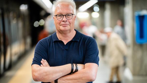 Peter Mertens staat met zijn armen gekruist in een metrostation