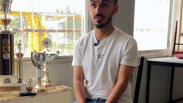 Hakan zit op een stoel in de voetbalkantine